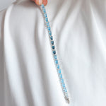 Blue gemstone bracelet held against a white fabric background