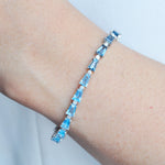 Model’s wrist wearing the 14K white gold blue topaz and diamond bracelet to demonstrate its elegant drape and sparkle.
