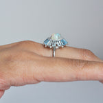 Close-up of the ring being worn, showing the prong set central opal.