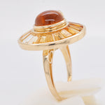 Top-down view of a circular gold ring featuring a honey-colored cabochon surrounded by baguette citrines.