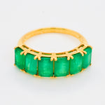 Macro shot of the faceted green emerald gems and the intricate 14K gold prong details.