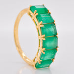 Side perspective of the 14K gold ring, highlighting the deep green color and cut of the emeralds.