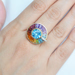 Model wearing rotating multi gemstone halo ring in 14K yellow gold