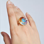 Lifestyle shot of rotating halo ring with blue topaz center.