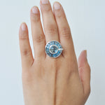 A model wearing the 14K white gold blue topaz statement ring on her middle finger, showing its scale.