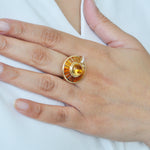 Gold ring with a circular design worn on a hand.