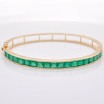 A detailed look at the geometric symmetry of the faceted green stones, emphasizing the minimal metal interference in the channel mounting.