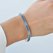 14k white gold blue topaz bracelet worn on a wrist to show scale and sparkle.