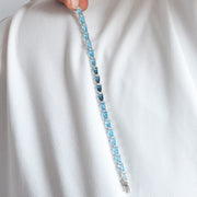 Blue gemstone bracelet held against a white fabric background