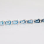 Focus on the precise bar-style setting of the blue topaz gems and the clarity of the surrounding diamond details.