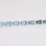 Focus on the precise bar-style setting of the blue topaz gems and the clarity of the surrounding diamond details.