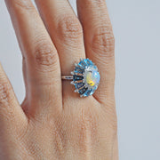 Lifestyle image of a hand displaying the unique opal, diamond, and blue topaz cocktail ring.