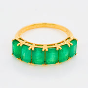 Macro shot of the faceted green emerald gems and the intricate 14K gold prong details.