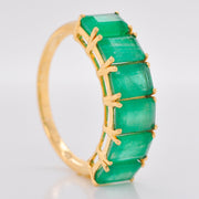 Side perspective of the 14K gold ring, highlighting the deep green color and cut of the emeralds.