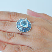 Close-up of a hand displaying the unique rotating blue gemstone ring against natural light.