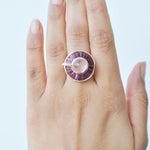 A model’s hand wearing the 14K gold rose quartz and rhodolite statement ring on the middle finger.
