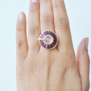 A model’s hand wearing the 14K gold rose quartz and rhodolite statement ring on the middle finger.