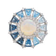 14K white gold statement ring with a central bezel-set opal surrounded by a halo of small diamonds & prong set blue topaz gemstone.