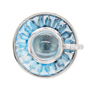 14K white gold rotating ring featuring a central cabochon blue topaz, channel-set tapered baguettes, and diamond accents.