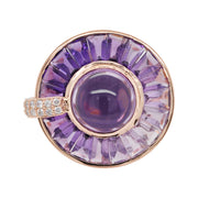 14K gold rotating ring with central amethyst cabochon, channel-set tapered baguettes, and diamond accents.