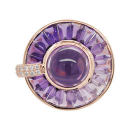 14K gold rotating ring with central amethyst cabochon, channel-set tapered baguettes, and diamond accents.