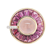 14K gold rotating ring with central cabochon rose quartz and channel-set tapered baguette rhodolite halo.